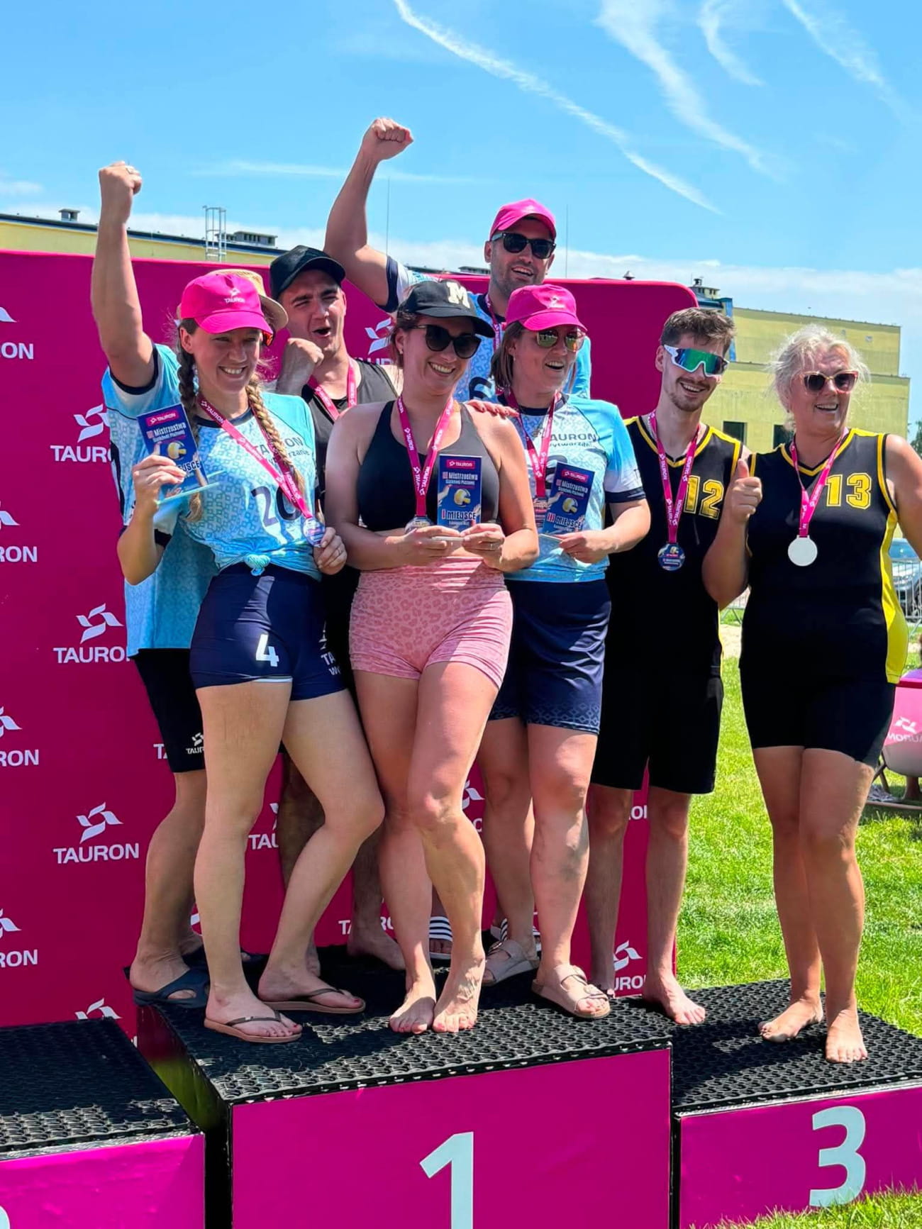 Pracownicy z medalami i statuetkami stoją na podium.